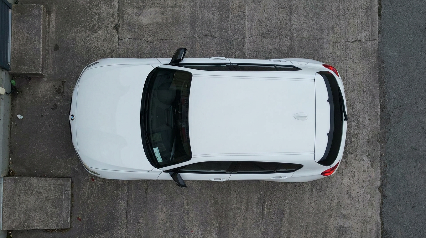 Top-down view of a white BMW M140i roof and tinted panoramic glass
