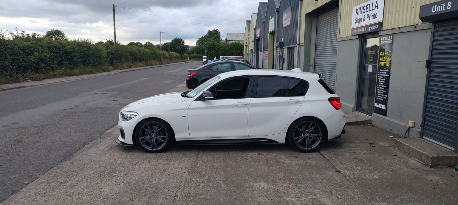 Front-left side profile of a tinted white BMW M140i M Performance hatchback